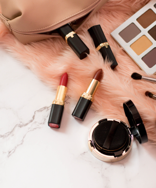 Flat lay of make up items on fur over marble surface